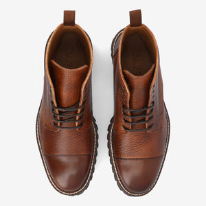 Top view of a pair of brown leather lace-up boots with textured and smooth sections, brown pull tabs, and stitched soles on a white background.