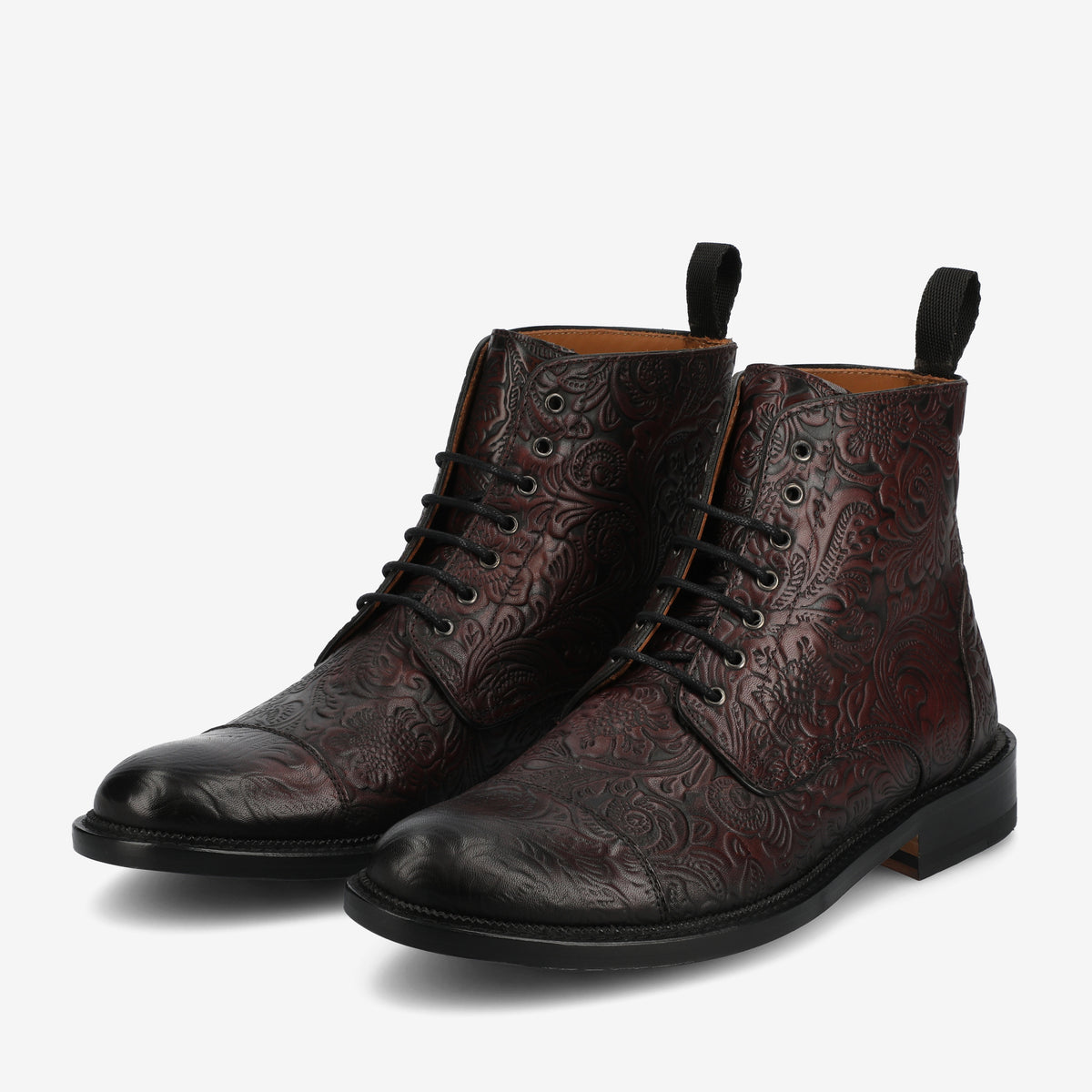 A pair of dark red leather lace-up boots with intricate embossed patterns, black toe caps, and black pull tabs on a white background.