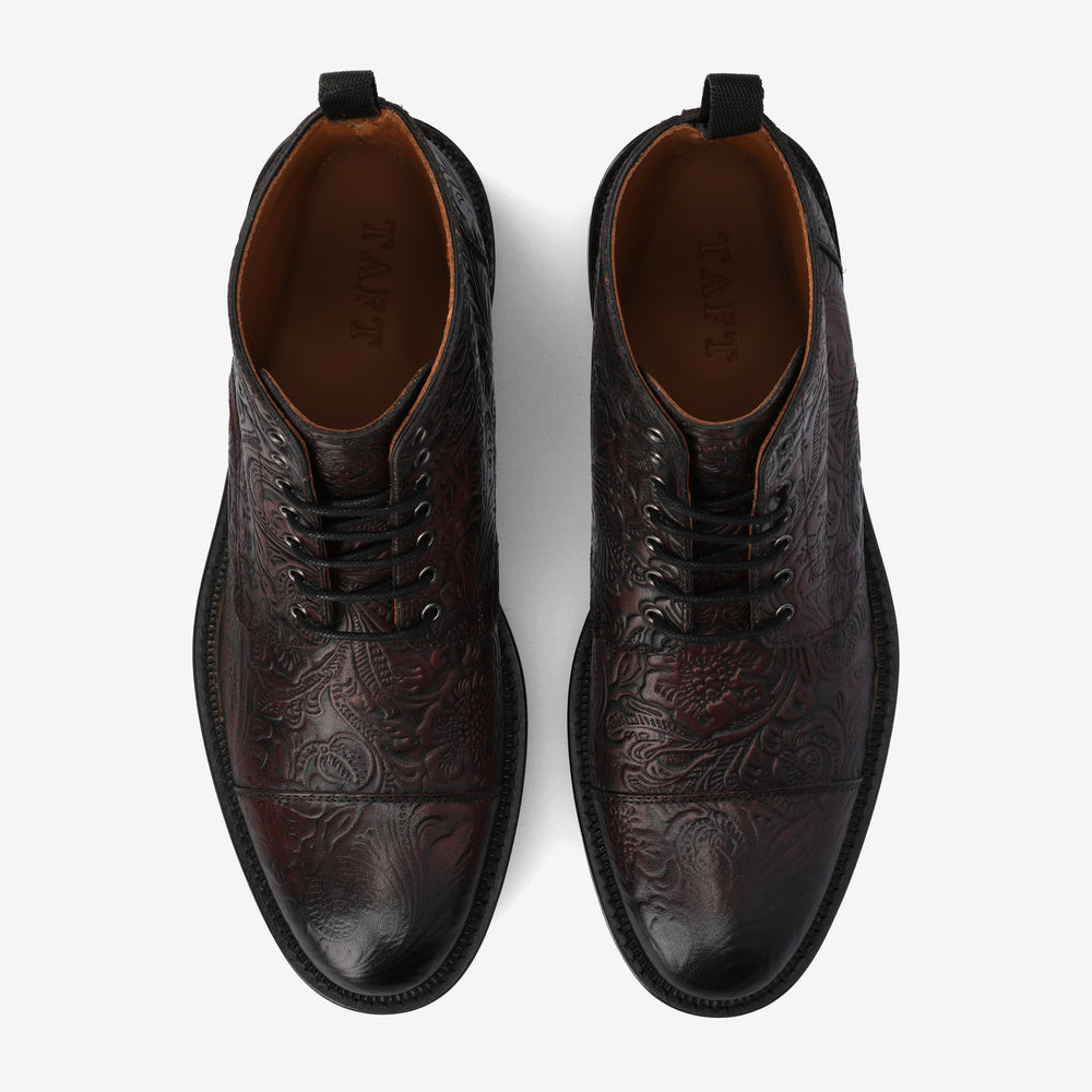 A pair of dark brown leather dress shoes with intricate floral engravings, viewed from above.