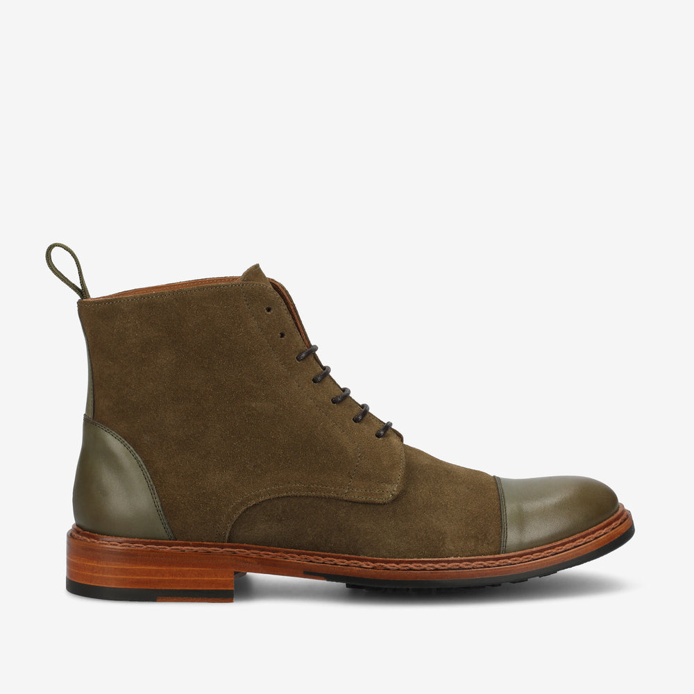 A single brown and olive green lace-up suede boot with a brown leather sole and a green loop at the back.