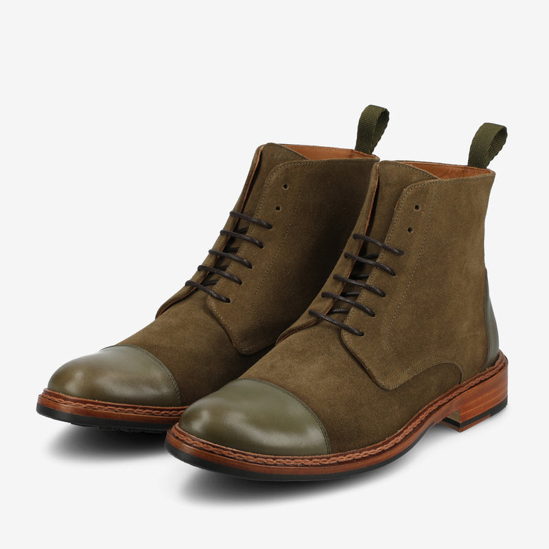 A pair of green suede leather lace-up boots with brown wooden soles, featuring dark green toecaps and pull tabs at the back.