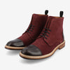 A pair of burgundy suede boots with black leather toe caps and laces, featuring brown wooden soles and black pull tabs at the back.