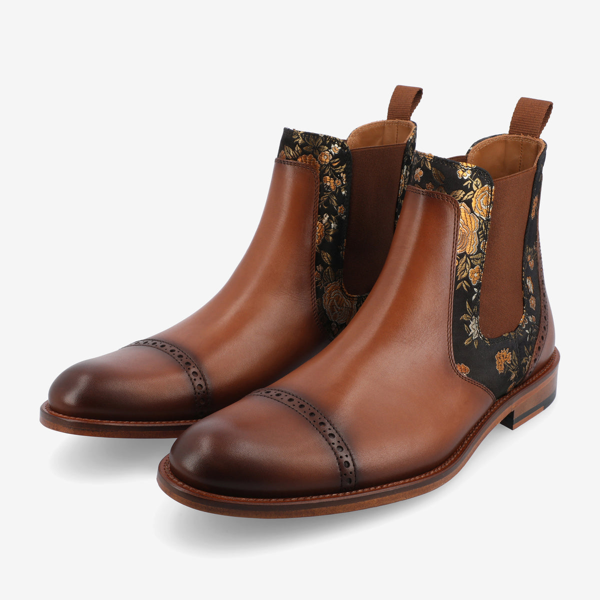 A pair of brown leather Chelsea boots with floral pattern fabric inserts and a reeded toe cap design.