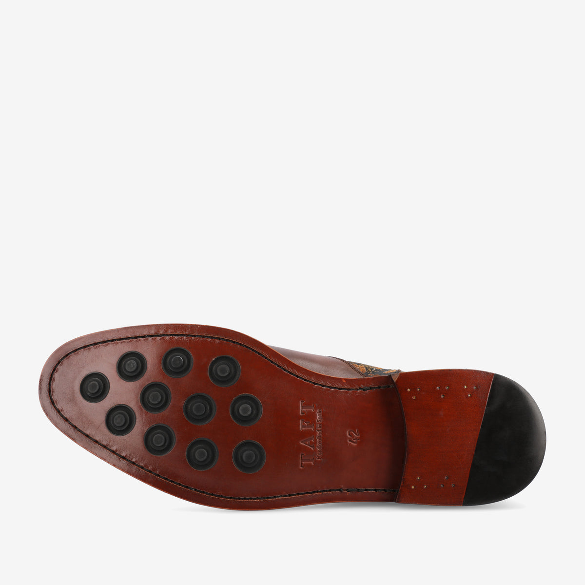 The image shows the sole of a brown leather dress shoe with black rubber studs for traction and the brand name TAFT embossed on it.