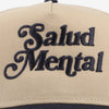 Close-up of a beige cap with black embroidered text that reads Salud Mental.