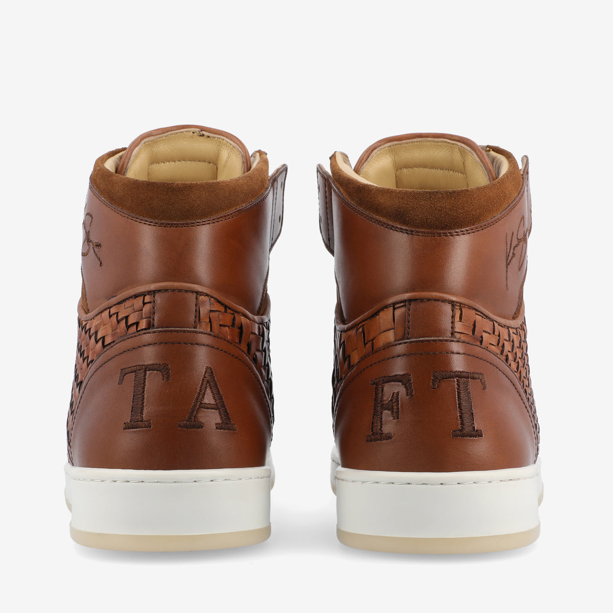 A pair of brown leather high-top sneakers with intricate woven detailing and embroidery, displaying the letters TAFT on the back.