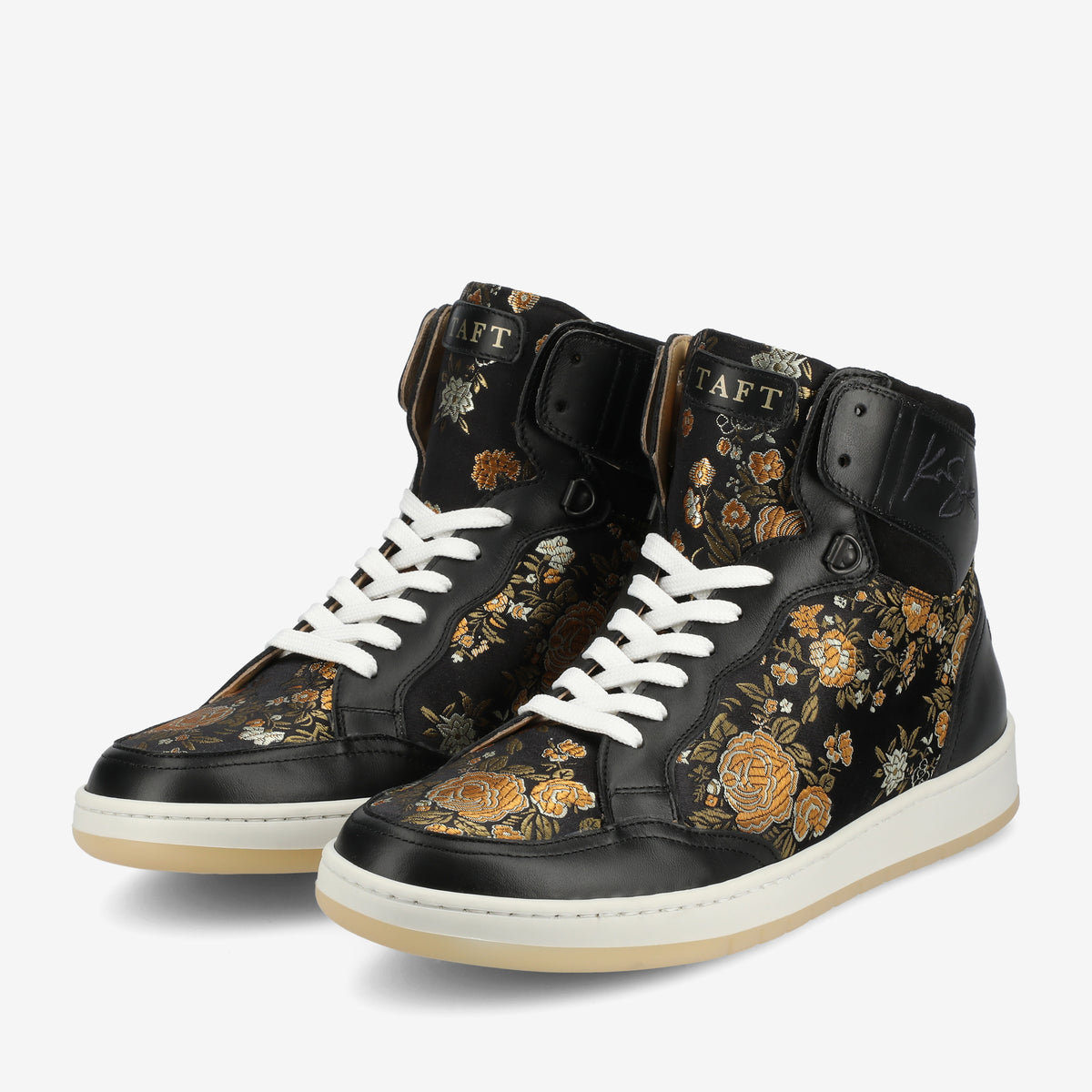 A pair of black high-top sneakers with white soles and laces, featuring a floral design with gold and orange accents, and a TAFT logo on the tongue.