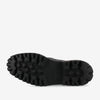 The image shows the sole of a black boot with a rugged, textured tread pattern.