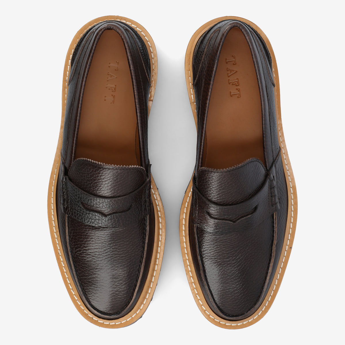 Top view of a pair of dark brown leather loafers with light brown soles, displaying the TAFT brand name printed on the insole.