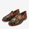 A pair of black loafers with a gold floral pattern, featuring brown leather straps and wooden soles.