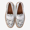 Top view of a pair of white and gray loafers with a floral lace pattern, brown soles, and the brand name embossed inside.