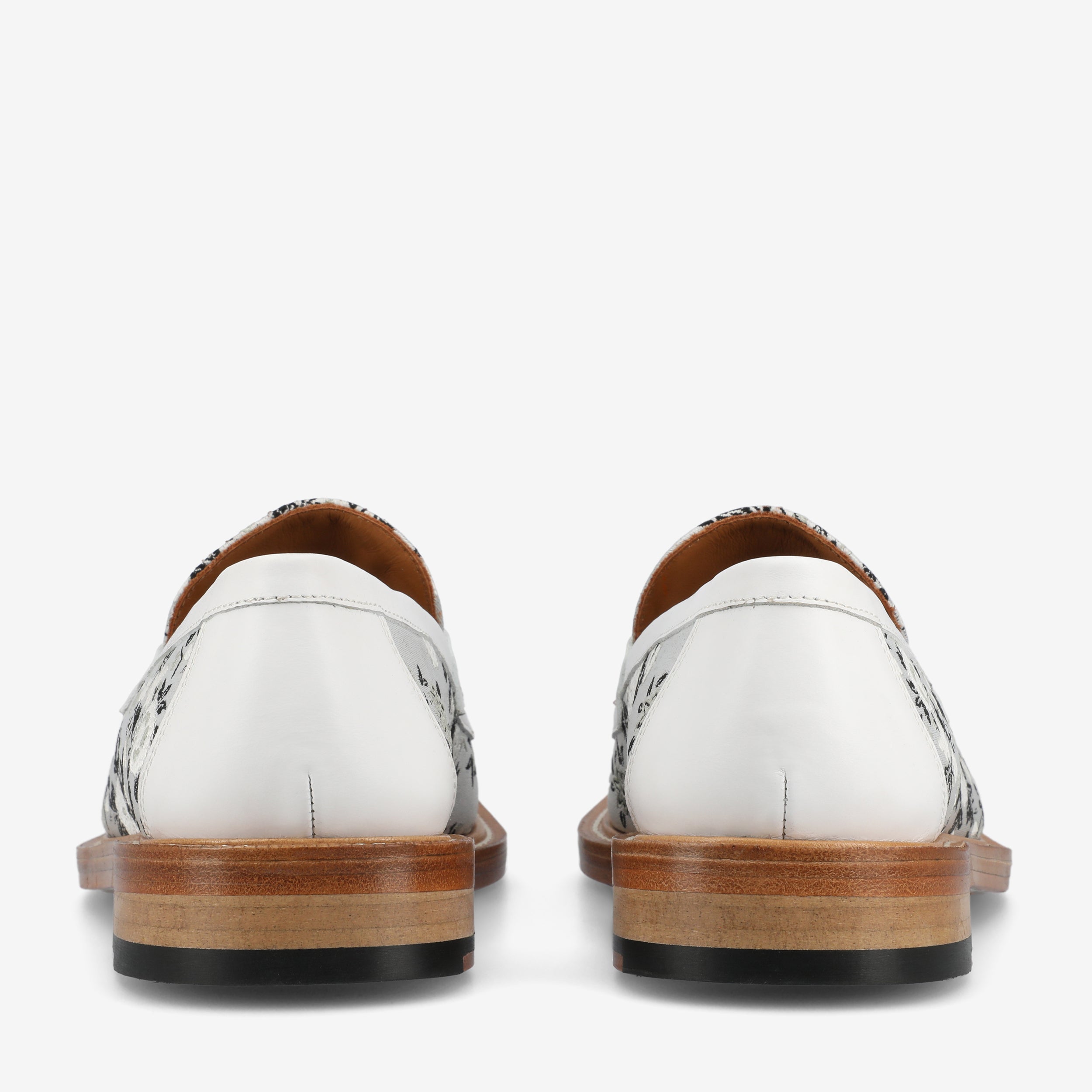 Back view of a pair of white leather loafers with wooden soles and black patterned details.