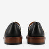 Rear view of two black leather loafers with wooden soles and a patterned section on the sides.