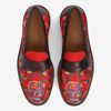 A pair of red loafers featuring a floral pattern with multicolored flowers and a dark brown leather strap across the top. The brand TAFT is visible on the insole.