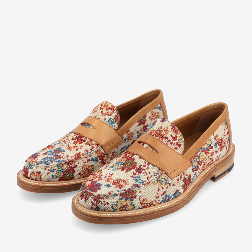 A pair of loafers with a colorful abstract pattern and light brown leather detailing.