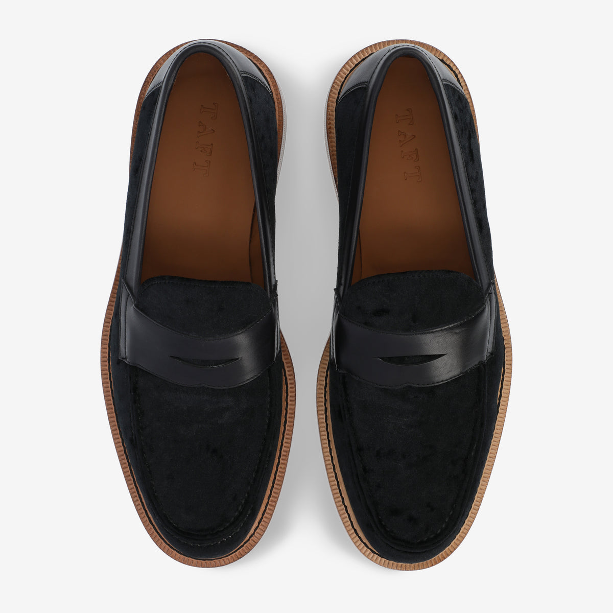 A pair of black leather loafers with brown soles, viewed from above.