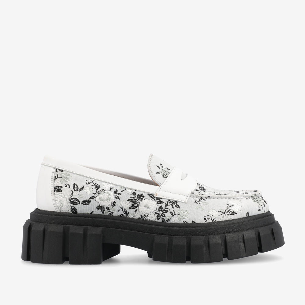 A white loafer with a black floral pattern and a chunky black sole.