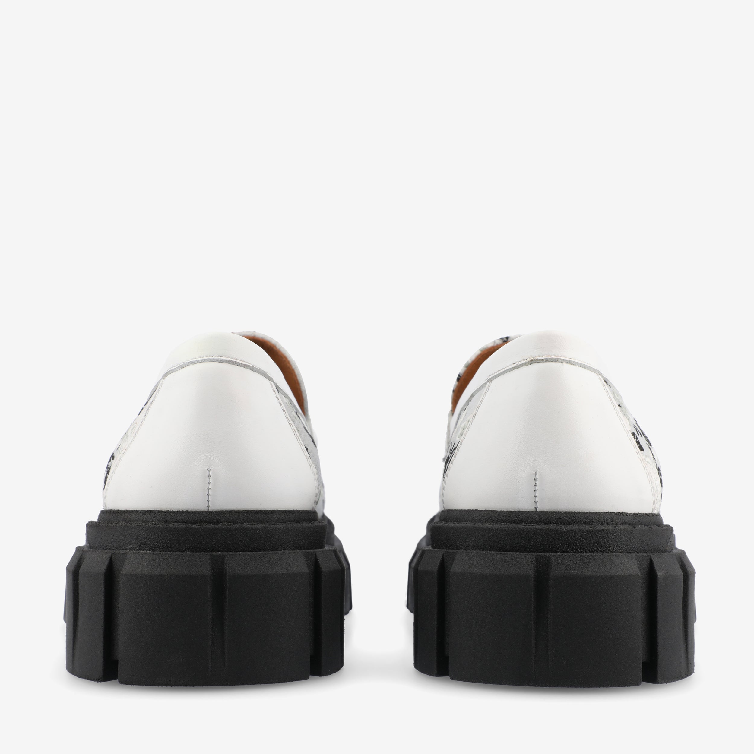 Rear view of a pair of white platform shoes with chunky black soles.