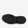 The image shows the bottom view of a black rubber sole of a shoe, featuring a rugged tread pattern with deep grooves for added traction.