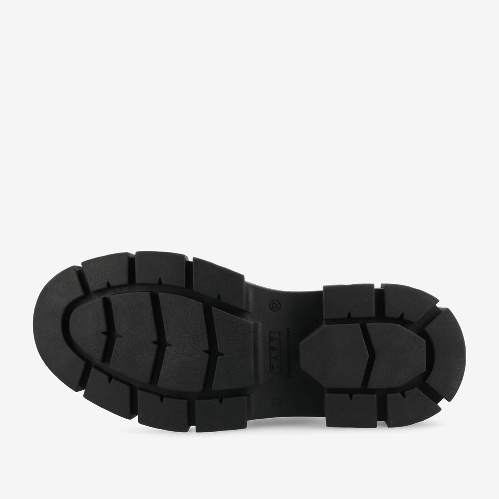 Bottom view of a heavy-duty black rubber shoe sole with thick, prominent treads and grooves for enhanced grip and durability.