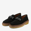 A pair of black suede loafers with metal chain accents and light brown crepe soles.