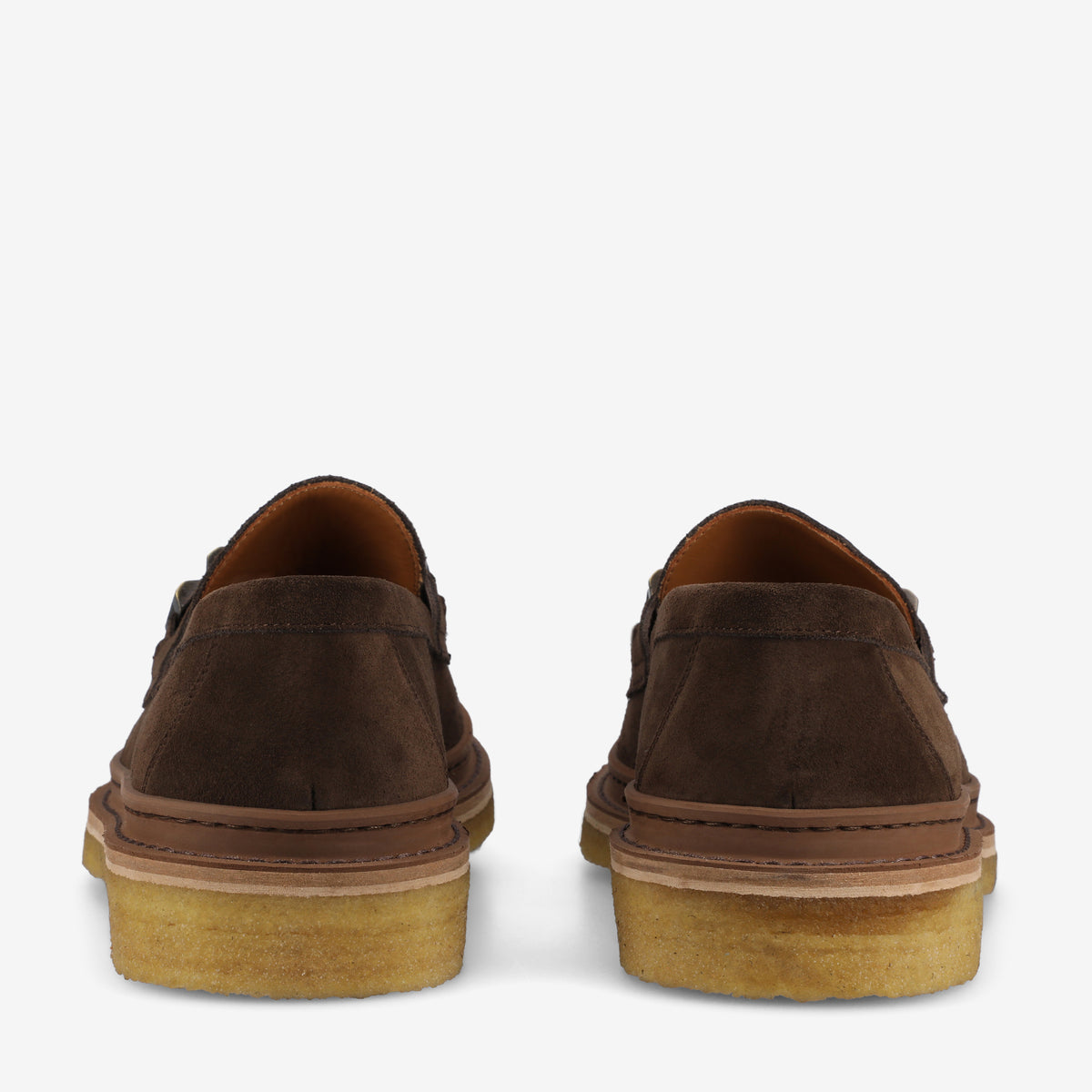 Rear view of a pair of brown suede loafers with light-colored rubber soles on a white background.