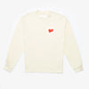 A long-sleeved, cream-colored shirt with a small red heart graphic and white text encircling it on the left chest area, laid flat.