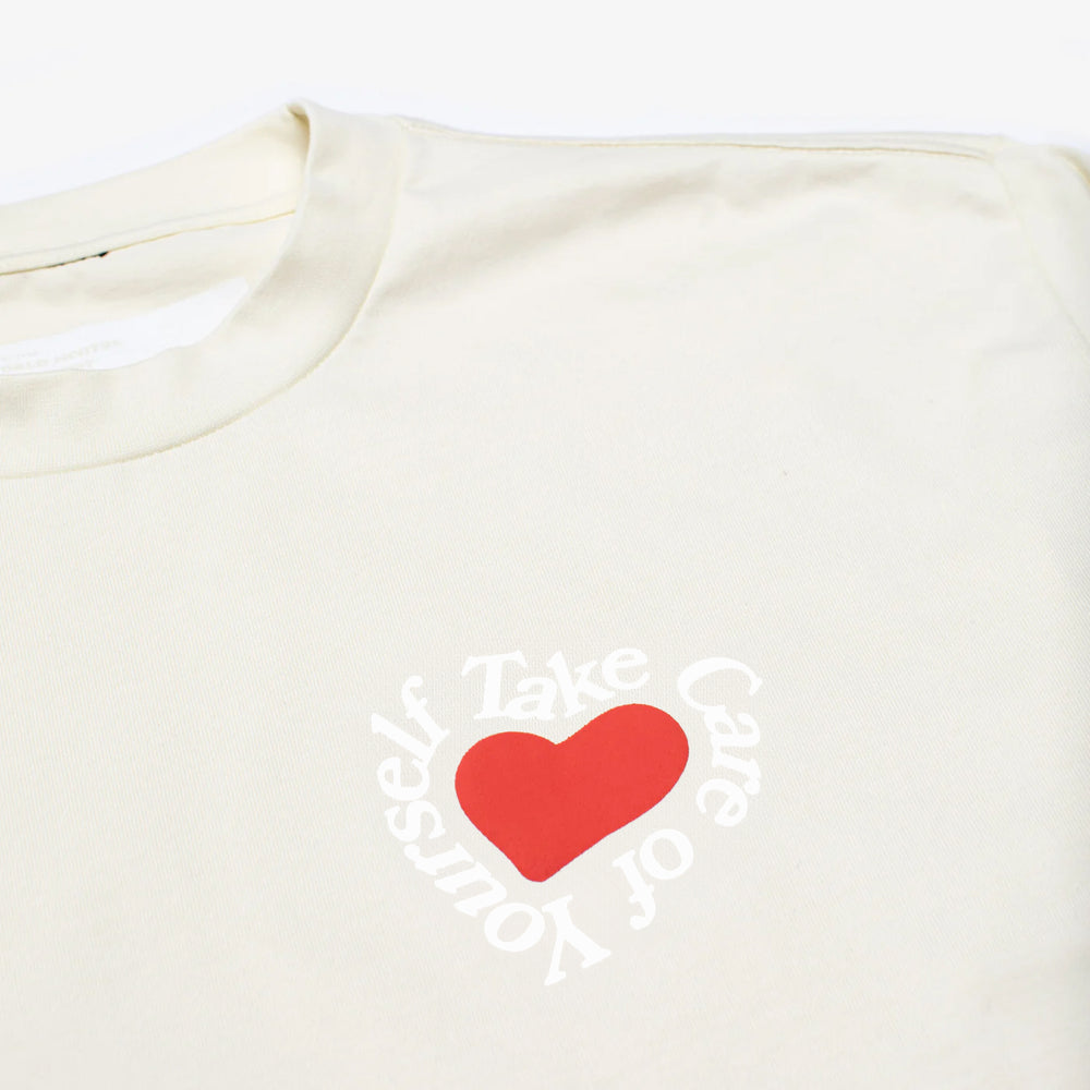 A white shirt featuring a red heart with the words Take Care of Yourself printed around it in a circular pattern.