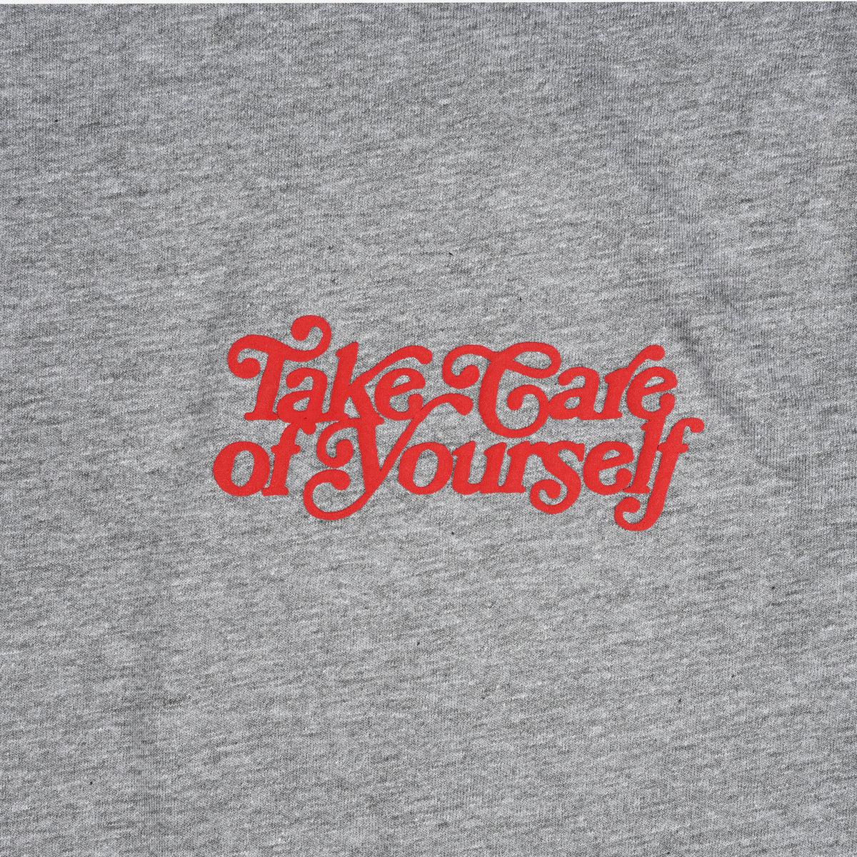 A gray fabric with the red text Take Care of Yourself printed in stylized cursive font.