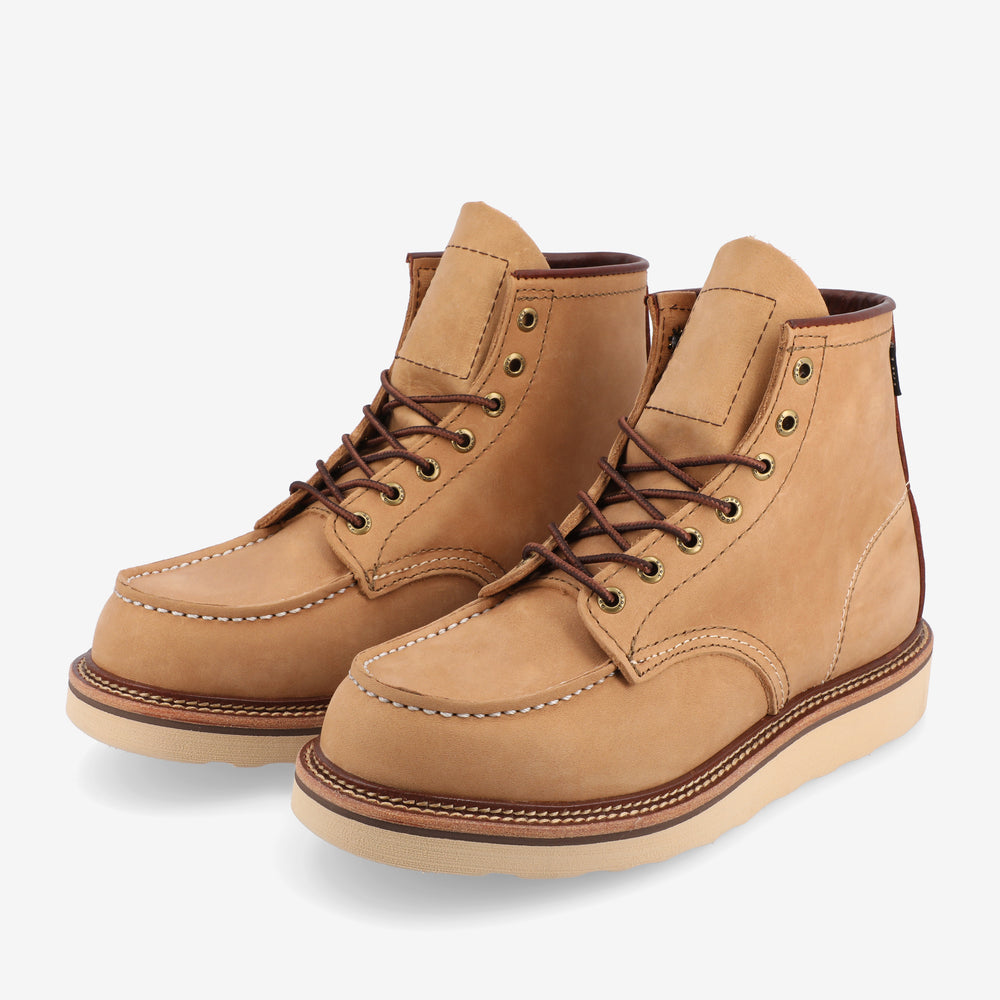 A pair of tan leather lace-up boots with white soles, featuring brown laces, metal eyelets, and detailed stitching.