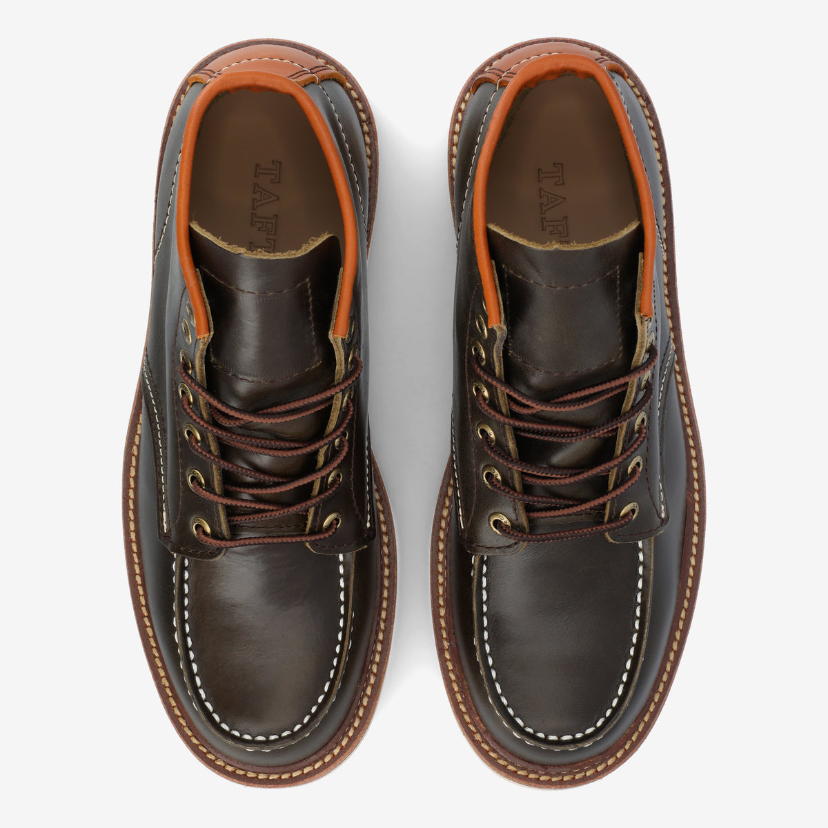 Top view of a pair of dark brown leather boots with tan accents, white stitching, brown laces, and a rugged sole.