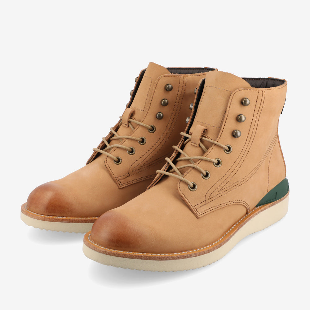 A pair of tan leather lace-up ankle boots with white soles and green heel accents on a white background.