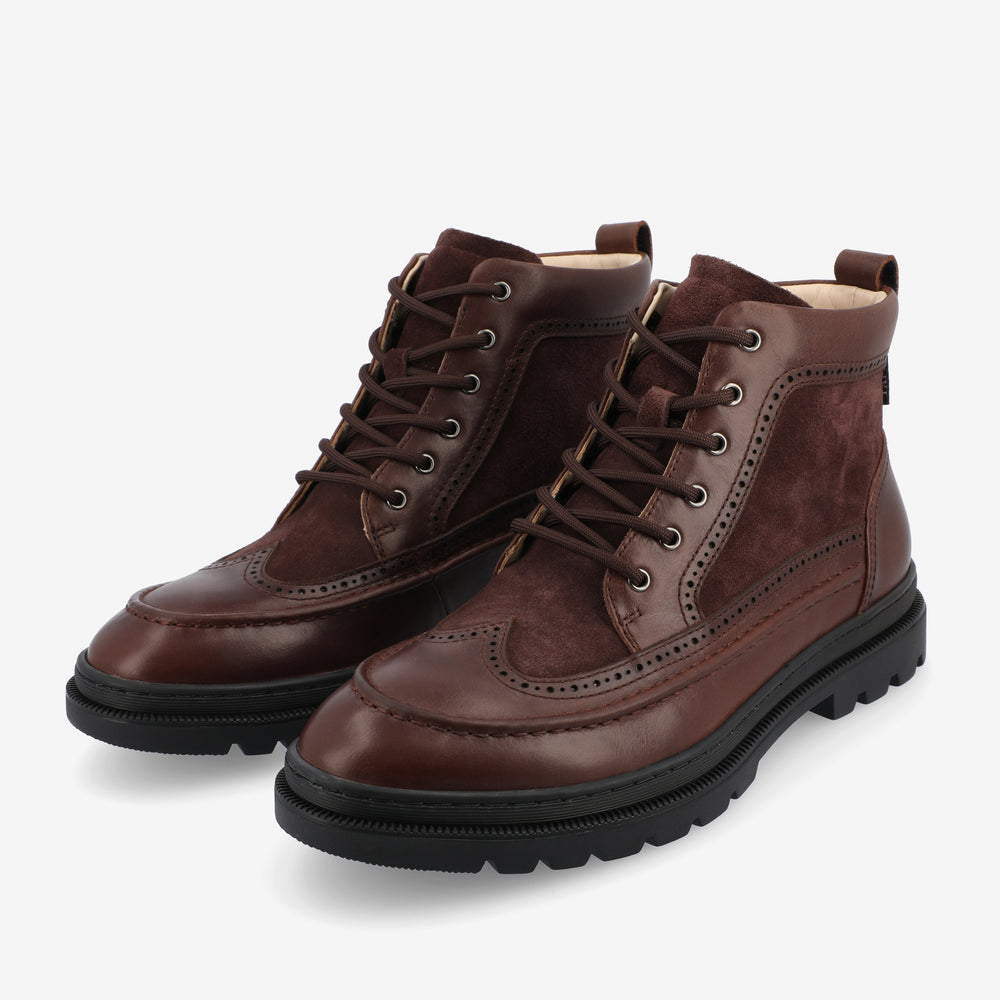 A pair of brown leather and suede lace-up boots with rugged black soles, positioned on a white background.