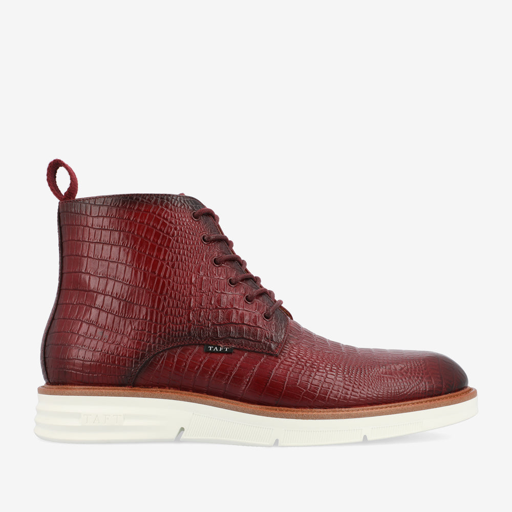 Side view of a single, maroon-colored, crocodile-textured leather boot with dark laces and a white rubber sole.