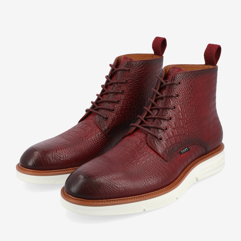 A pair of maroon, high-top leather shoes with a textured pattern, white soles, brown trim, and pull tabs at the back.