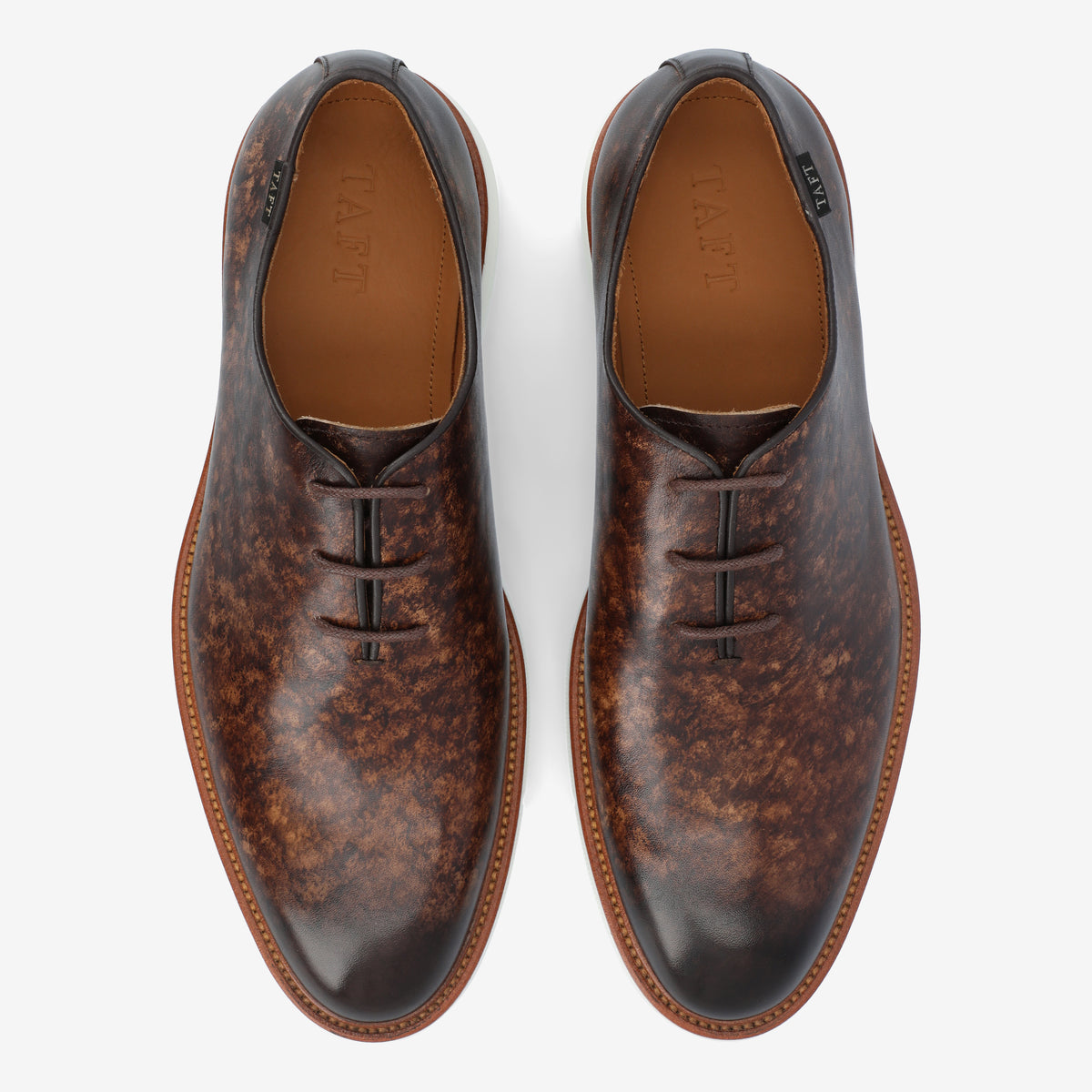 Top view of a pair of brown leather dress shoes with a mottled pattern, three eyelets for laces, and tan leather soles.