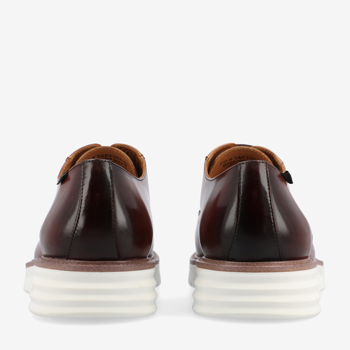 Rear view of a pair of brown leather shoes with white, cushioned soles displayed on a white background.