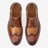 Top-down view of a pair of brown leather brogues with intricate perforation designs and the word TAFT engraved inside.