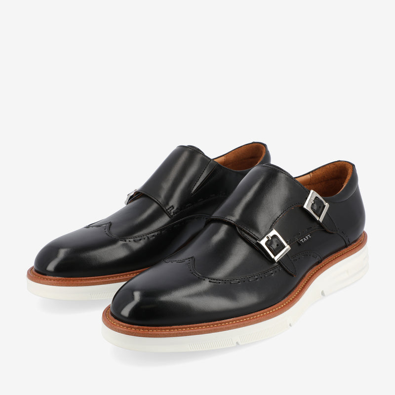 A pair of black leather monk strap shoes with white soles and decorative brogue detailing.