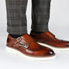 A person wearing brown leather double monk strap shoes with plaid trousers.