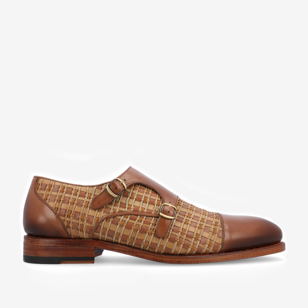 A brown leather dress shoe with a woven pattern, featuring two side buckles, and a wooden heel.