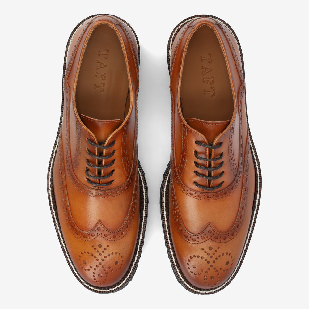 A pair of tan leather brogue shoes with intricate perforated patterns, black laces, and the brand TAFT embossed on the insole. The shoes are displayed from a top-down view against a white background.