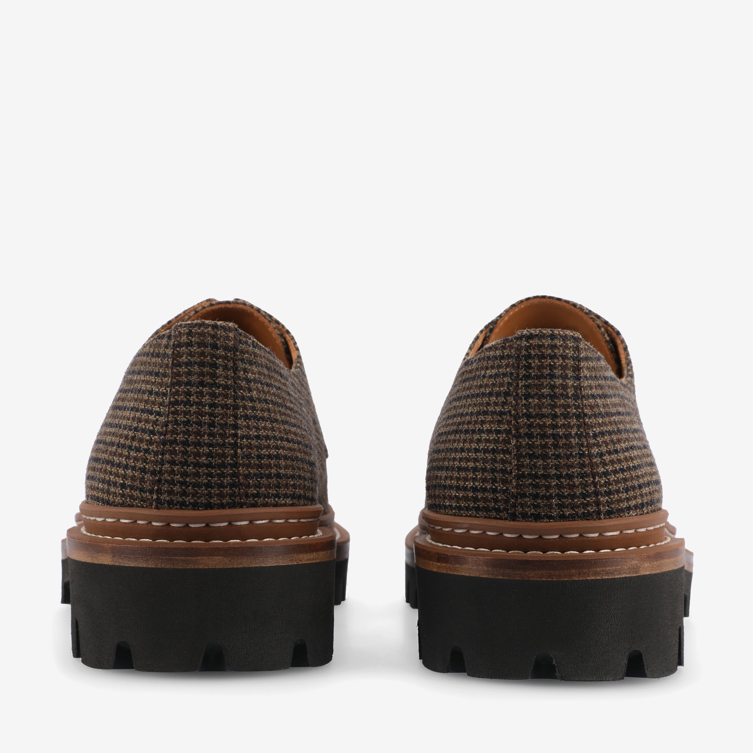 Rear view of a pair of brown and black houndstooth pattern shoes with chunky black soles against a white background.