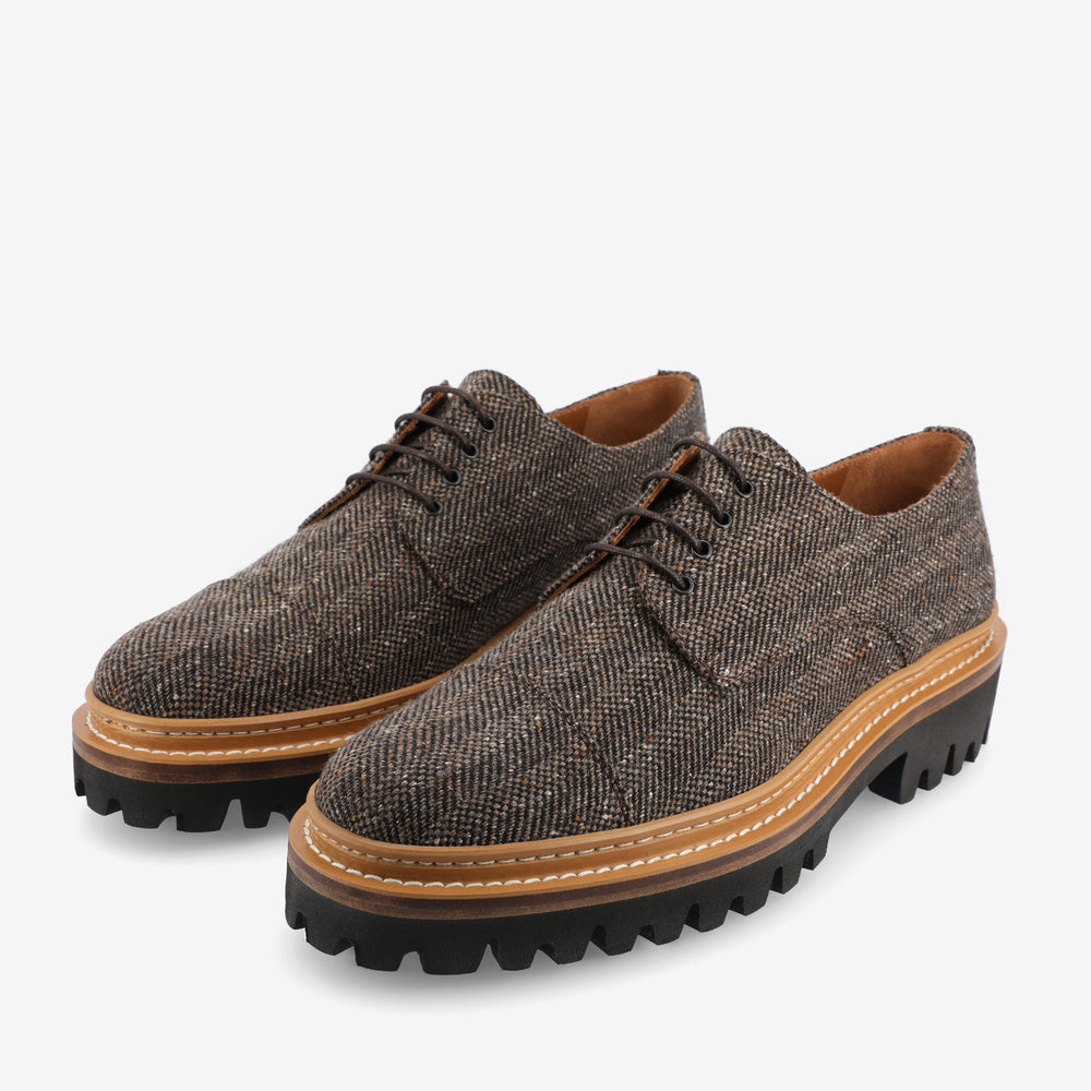 A pair of brown tweed lace-up shoes with black chunky soles and tan detailing.