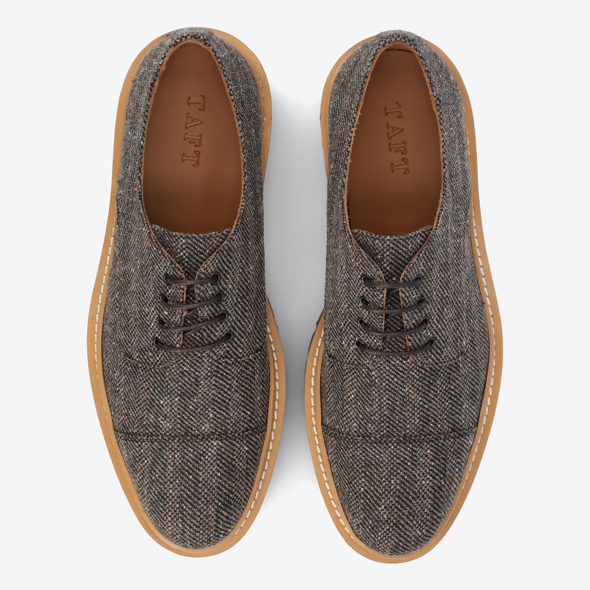 Top view of a pair of gray-brown tweed lace-up shoes with tan soles and TAFT inscribed on the insoles, placed on a white background.