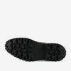 The image shows the rugged sole of a black shoe with deep treads, featuring multiple patterns including small cross shapes, designed for enhanced grip and durability.