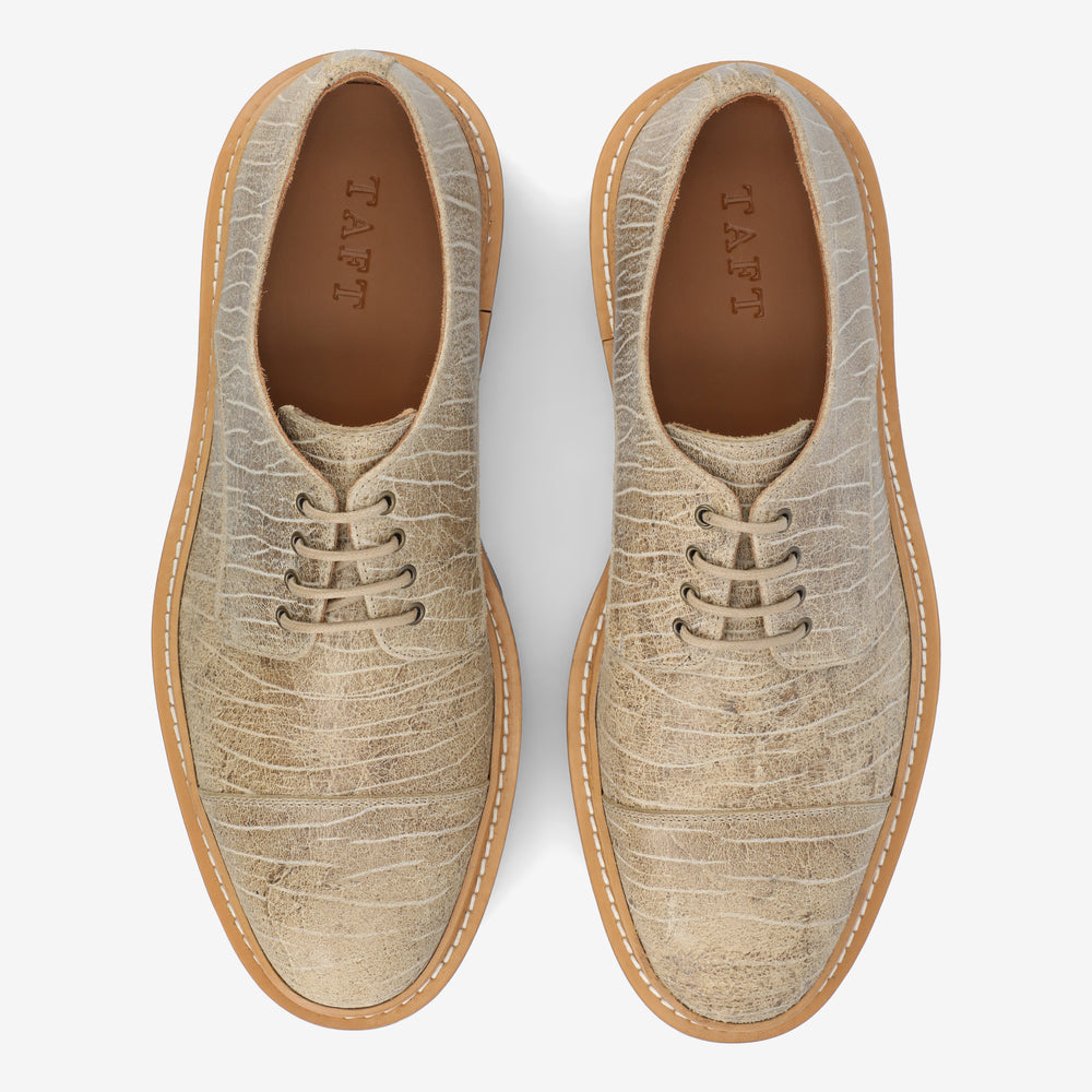 Top view of a pair of light beige textured leather shoes with laces and beige rubber soles, displaying the brand name TAFT inside.