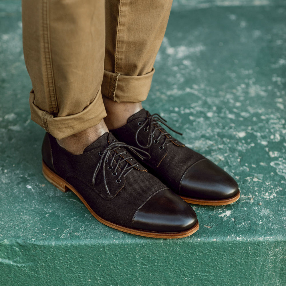 Man wearing black leather oxford shoes with brown soles and khaki pants.