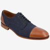 A single brown and navy blue cap-toe oxford shoe with laces, wooden sole, and contrasting textures on a plain white background.