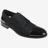 A black men's dress shoe with a cap toe and lace-up closure, featuring a combination of matte fabric and glossy leather on the toe and heel.